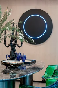 A modern living room featuring a black bowl with a glass base, illuminated by a contemporary glass lighting fixture.