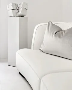 Contemporary living room with a modern white couch, grey throw pillows, and a geometric concrete sculpture