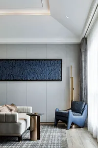 A modern living room featuring a fabric wall art piece and a combination of furniture with a blue accent chair and a white so