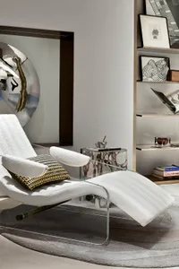 A contemporary living room featuring a stylish glass acrylic chair with a white cushion and throw blanket, placed on a round