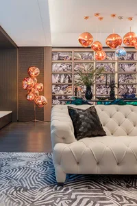 A modern living room with a white leather couch, black pillow, and decorative carpet.