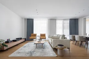 Modern living room with wooden furniture, leather chairs, and a white sofa.