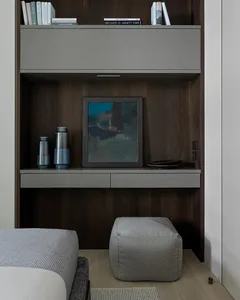 A modern minimalist living room with a grey couch, white ottoman, and indoor plant.