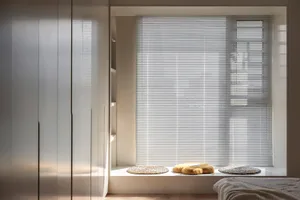 Minimalist bedroom with wooden blinds and plush cushions.