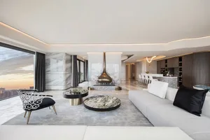 Modern living room with marble surfaces and a high ceiling.