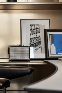 A modern office space featuring a metallic floating shelf and a sleek, curved concrete counter.