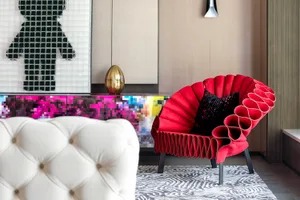 A red, contemporary armchair with black and white patterns on a rug in a living room.