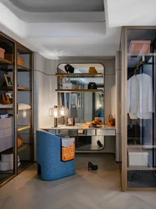 Modern closet space with organized storage, glass and metal accents, and a comfortable seating area.