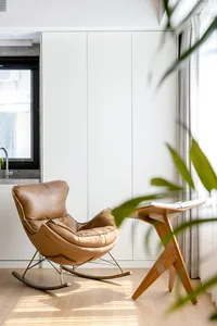 A minimalist home office with a comfortable wooden rocking chair and a sleek desk.