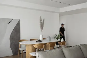 A minimalist living room featuring wooden furniture and a vase with dried grasses on a table.