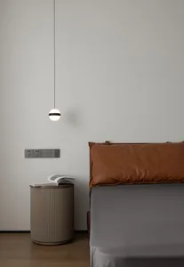 A modern bedroom featuring a brown leather cushion on a grey bed, photographed with a minimalist design style.