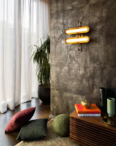 A modern living room with a concrete wall, wooden flooring, and floor-to-ceiling windows with sheer curtains.