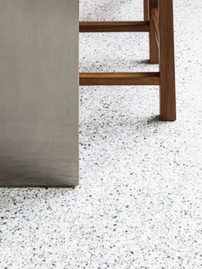 A modern floor with white terrazzo design, featuring a chair with wooden legs and a metal cabinet.