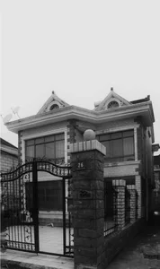 A modern residential house with a brick and concrete exterior featuring a double-story design and a gated entrance.