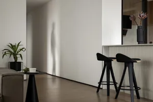 Modern kitchen with concrete countertops and wooden stools.