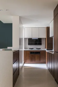Modern kitchen interior with white cabinets, wooden accents, and marble countertops.