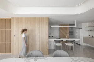 A modern kitchen with marble countertops, wood cabinetry, and stainless steel appliances.
