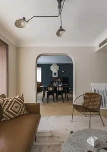 Contemporary living room featuring a brown leather couch, wooden accents, and a round textured coffee table.