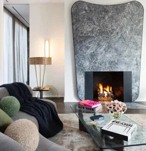 A modern living room featuring a marble fireplace and a comfortable sofa with cozy pillows.