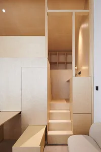 A minimalist residential interior with wooden stairs and storage units.