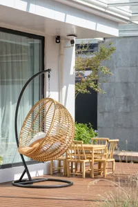 Bamboo-woven hanging chair and wooden dining set on a wooden patio