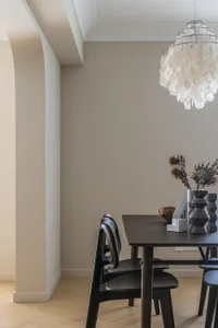 Modern dining room featuring a marble table with black chairs and a large, decorative chandelier.