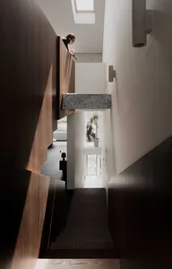 Photograph of a modern interior staircase with wooden steps and a concrete wall.