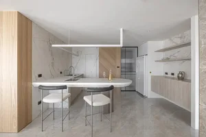 Modern kitchen with marble countertops, wooden cabinets, and stainless steel appliances.