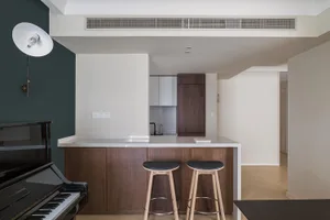 Modern kitchen featuring wood and white cabinets, white countertops, and black stools.