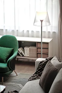A modern living room with fabric cushions on the sofa, a metal frame armchair, and a glass lamp shade.