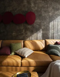 A cozy, modern living room featuring a caramel-colored leather couch adorned with textured pillows, positioned against a wall