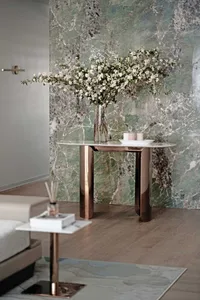 A modern living room featuring a metallic side table with a vase of white flowers and candles.