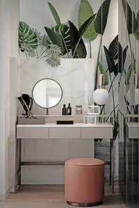 A modern vanity table with a round mirror, marble top, and pink stool.