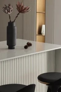 A modern minimalist kitchen with concrete countertops, wooden cabinets, and metallic accents.