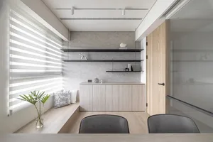 A minimalist office space with glass walls and wooden furniture, featuring a desk, chairs, and storage units.