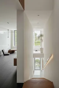 Modern white staircase with wood steps, white walls, and a light fixture.