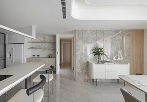 A modern residential kitchen featuring white marble countertops, shelves, and cabinets, with a minimalistic and elegant desig