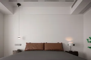 Minimalist bedroom with leather accents and a modern pendant light fixture.