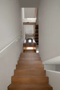 A modern wooden staircase interior with a minimalist design and white walls.