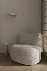 A modern interior with a textured fabric chair and minimalist lamp.