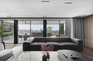 Modern living room featuring a grey sofa and glass walls overlooking a cityscape.