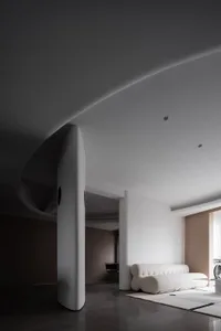 A minimalist living room with concrete walls and a white upholstered sofa.