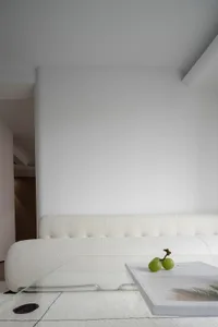 A modern white sofa lounge with a glass table displaying grapes and a book.