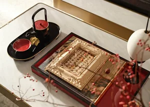 A beautifully decorated coffee table featuring a lacquer tray with calligraphy, a teapot, bowl, and branch with red berries.