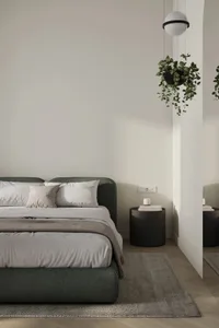 A minimalist bedroom with neutral colors and a black hanging plant.