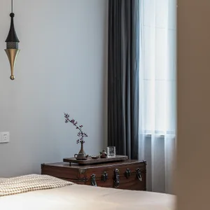 Minimalist bedroom with a wooden trunk decorated with tea set and vase.