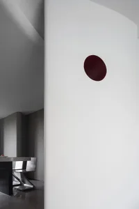 Minimalist food court with red circular light fixture on a white wall and white flooring.