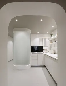 Modern kitchen with white cabinets, glass walls, and a minimalist design.