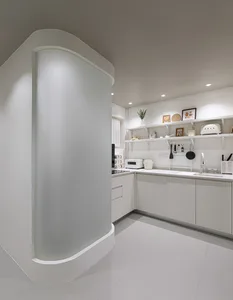 A minimalist kitchen with white textured marble counter and white cabinets.
