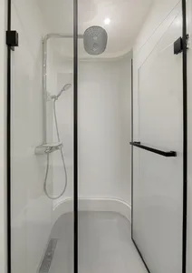 A sleek, minimalist bathroom with a glass shower enclosure and white fixtures.